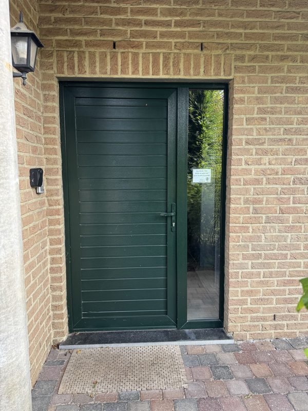 La porte d'entrée du cabinet, verte, avec une vitre sur le côté