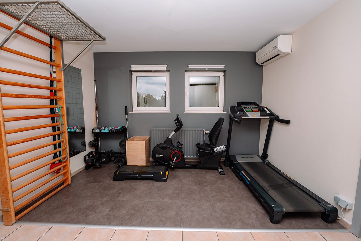 La salle d'exercice : espalier, vélo, tapis de course et haltères